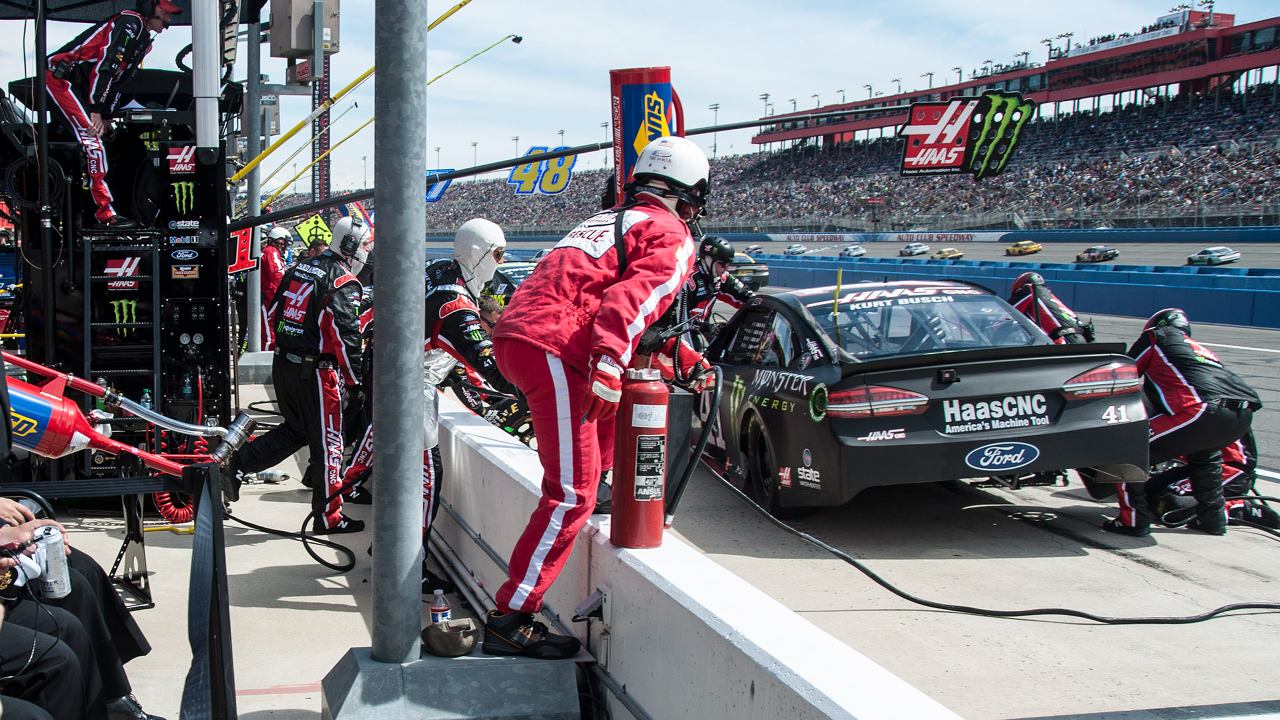 Sailors observe a NASCAR pit crew during the race.