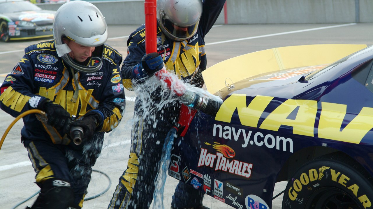 US Navy 050813-N-0962S-262 Fuel spills from the gas tank as pit crew members rush to get the No. 14 Navy Accelerate Your Life Dodge Charger back on the track