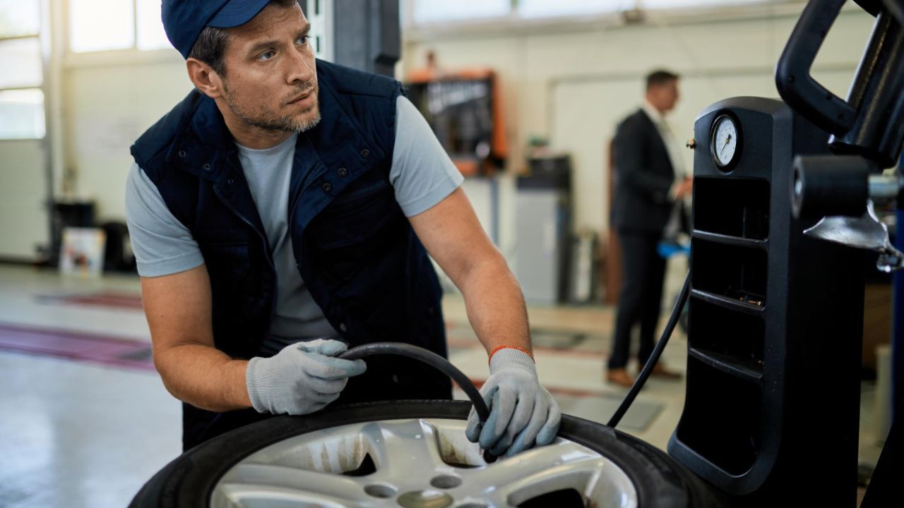 Car mechanic adjusting tire pressure