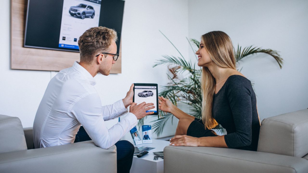 Man and woman in a car showroom using tablet