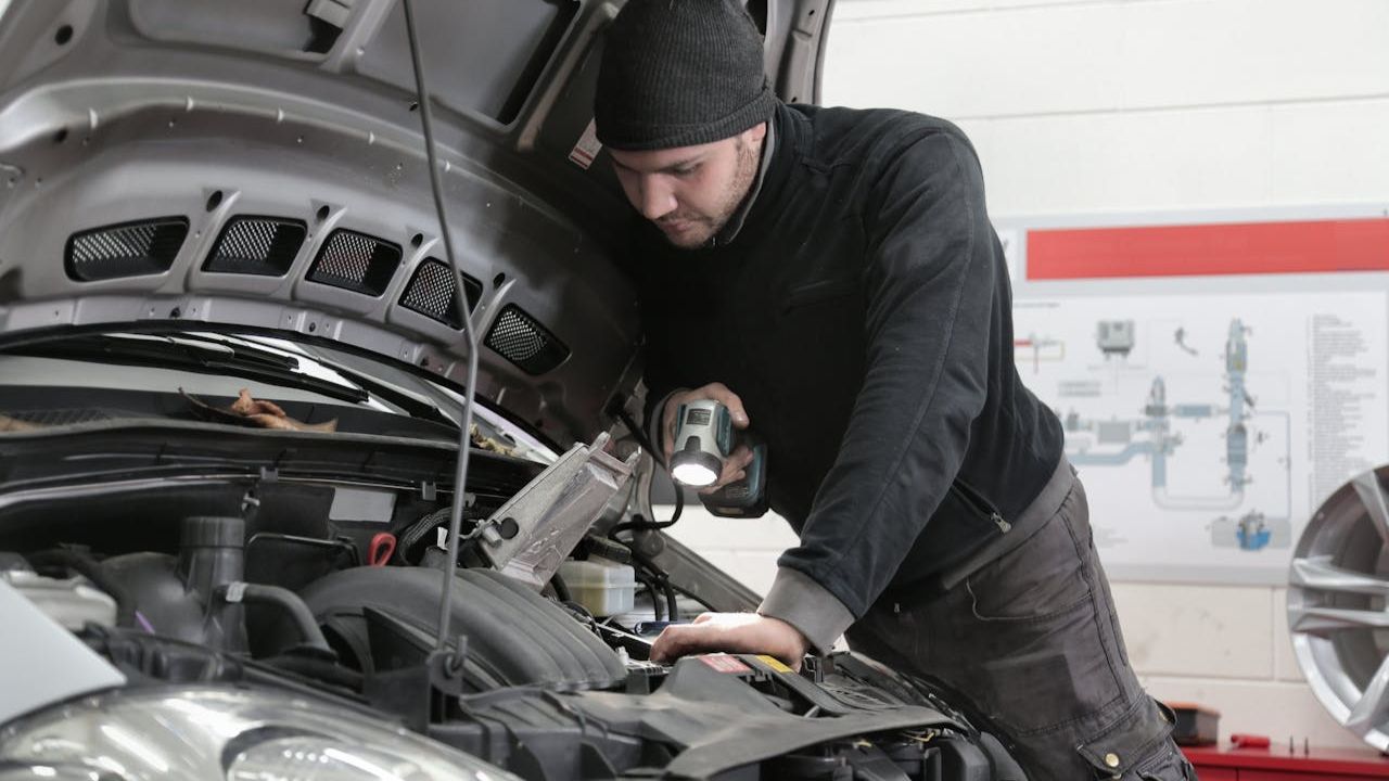 Man in Black Jacket and Black Knit Cap Inspecting Car Engine
