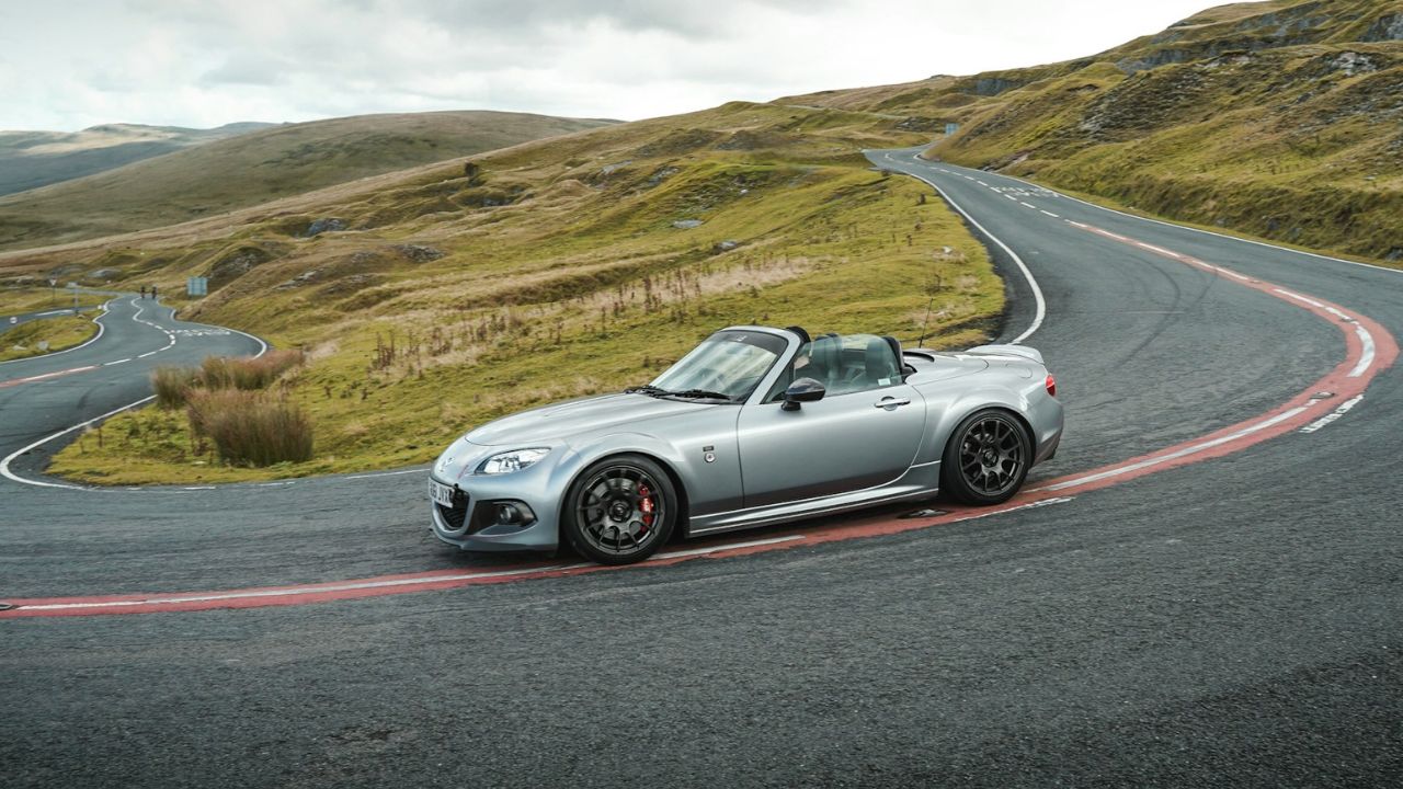 Silver convertible on a winding scenic road.
