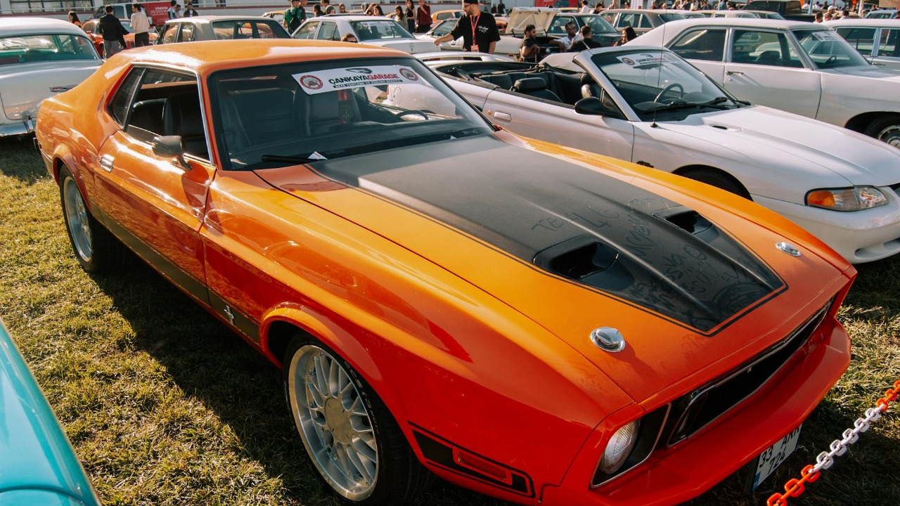 Vintage Ford Mustang Mach 1 displayed at an outdoor car exhibition.