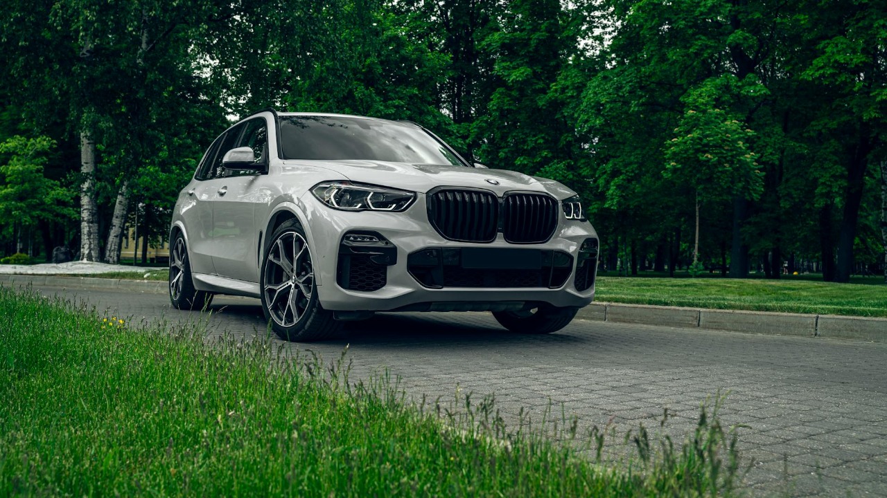 White BMW X5 SUV parked on a scenic road surrounded by lush greenery, showcasing elegance and style.