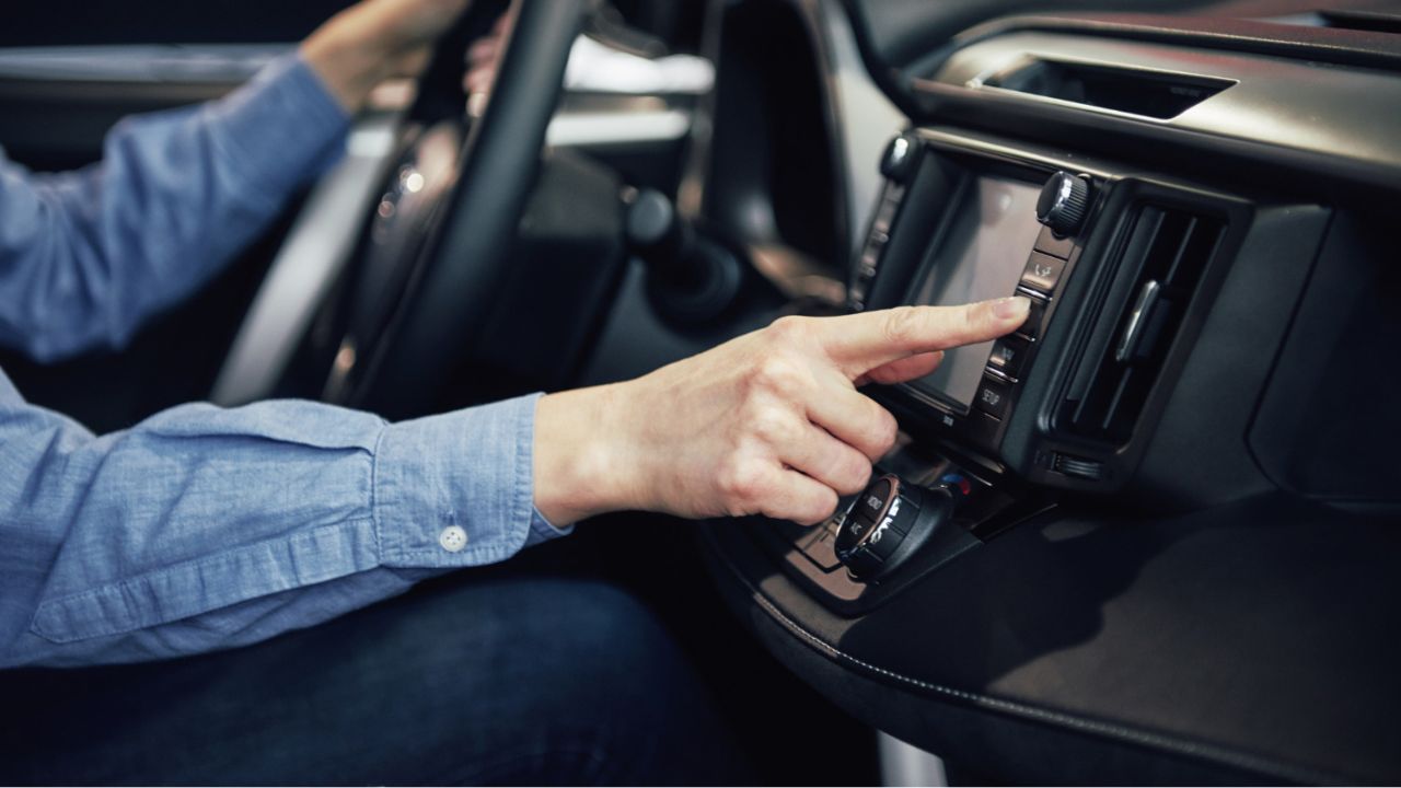 Person trying to press button on car dashboard