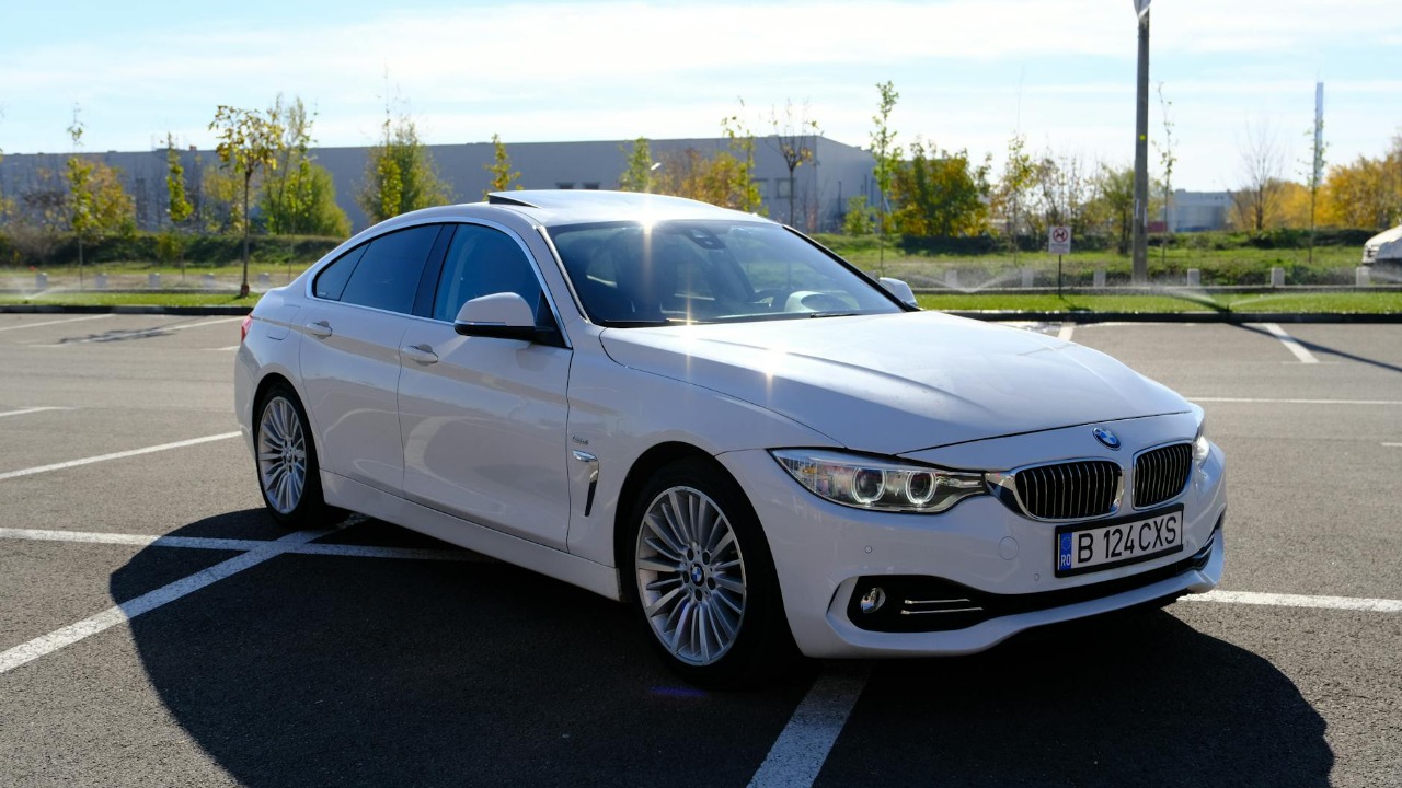 A white BMW parked under bright sunlight in a spacious outdoor parking lot.