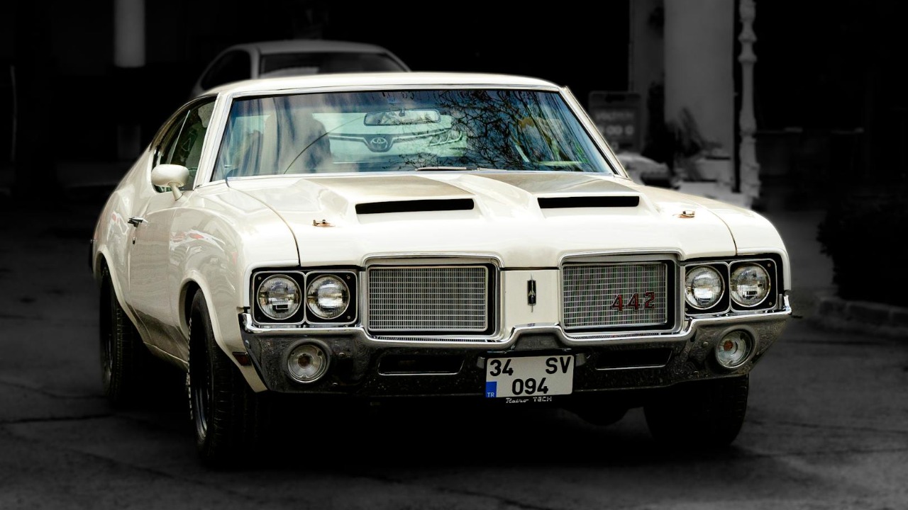 Front view of a classic Oldsmobile 442 muscle car in an urban setting.