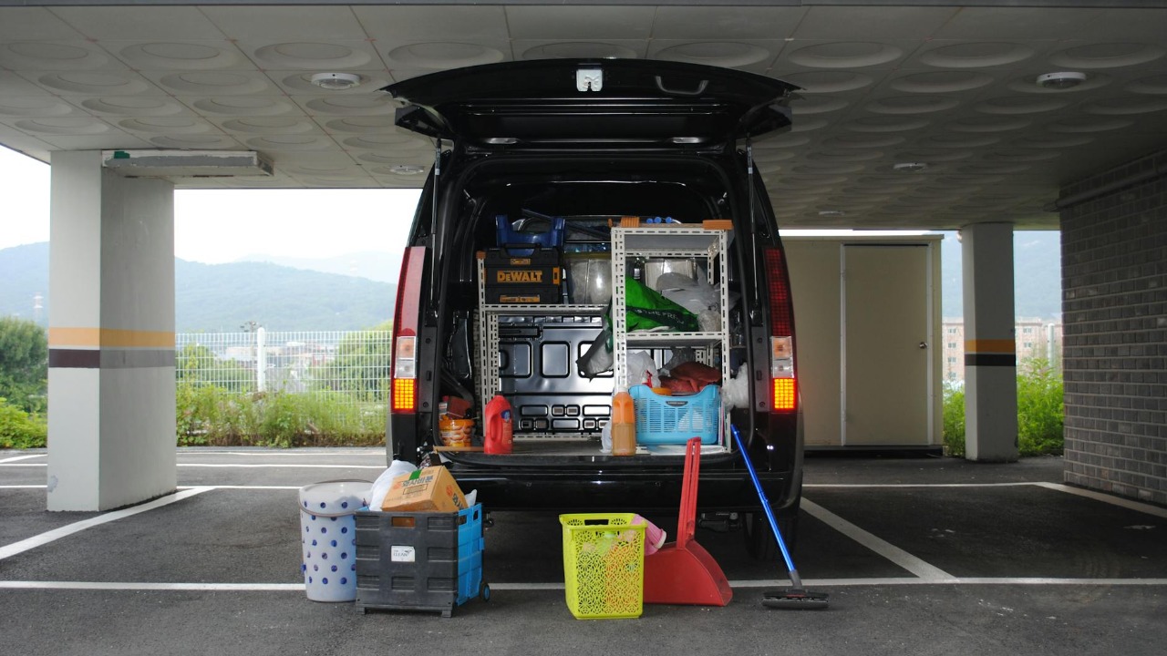 Back view of a black van with equipment in an urban parking area.