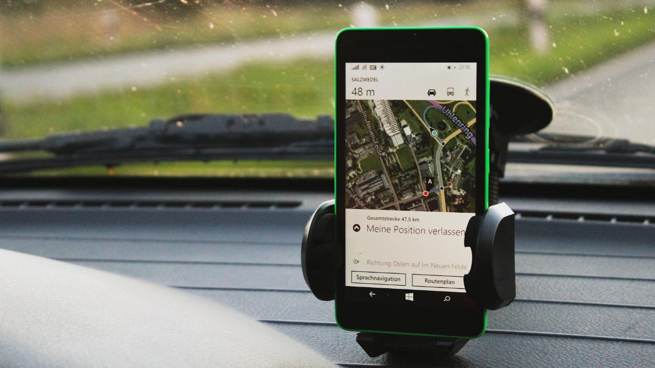 Smartphone with GPS navigation mounted on car dashboard, daylight view.