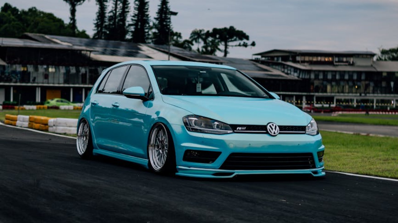 Striking blue Volkswagen Golf parked at a car meet in Brazil with a dramatic sky backdrop.