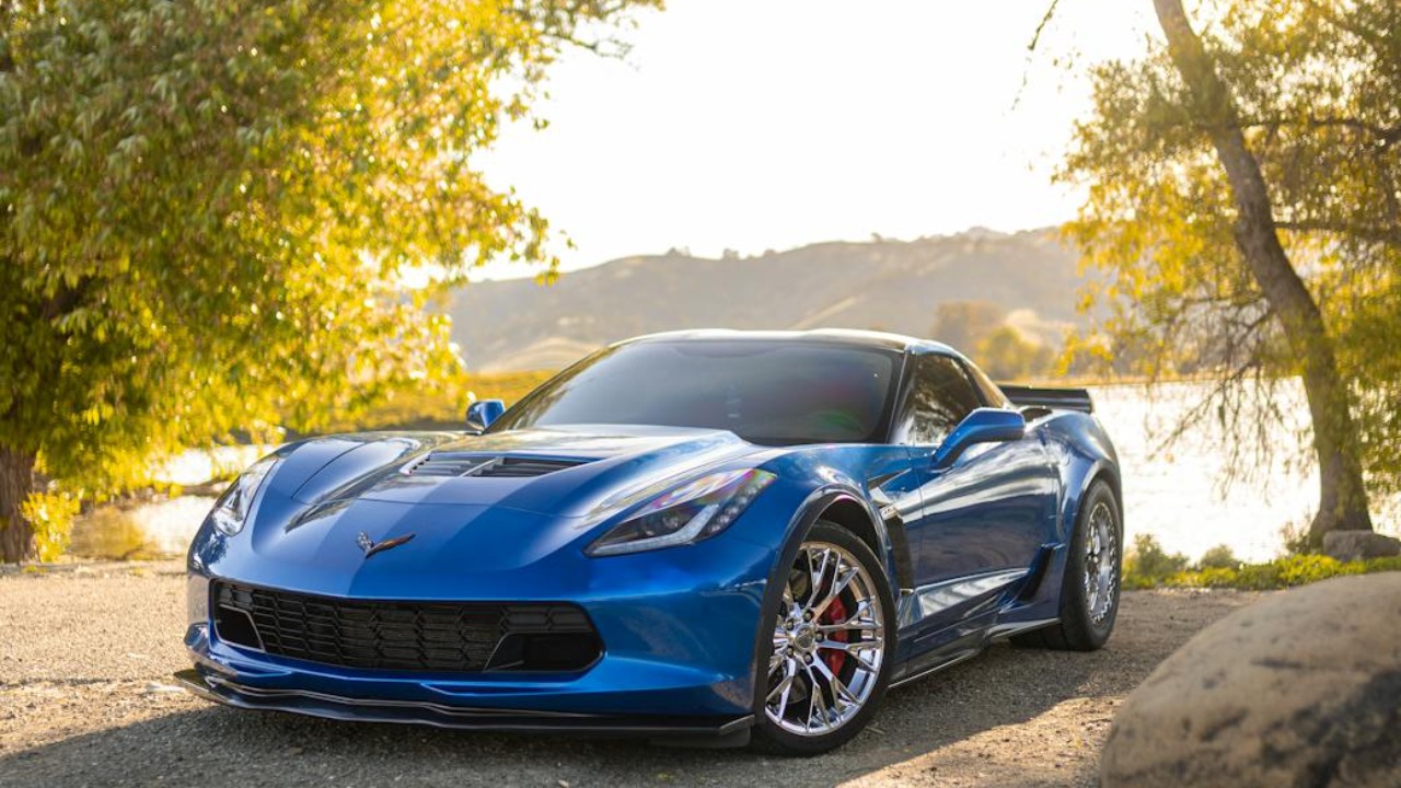 Stunning blue Chevrolet Corvette Z06 parked by a serene lake in rural setting.