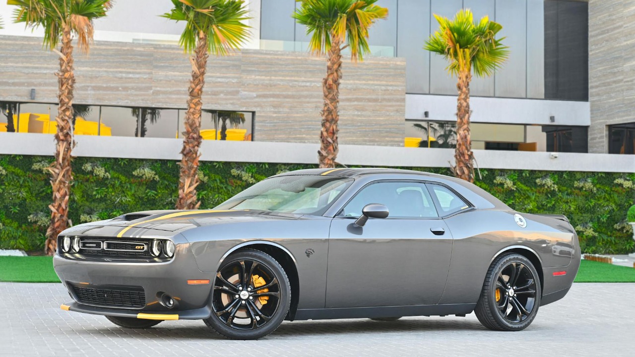 Stylish gray Dodge Challenger parked in a modern Dubai location with palm trees.