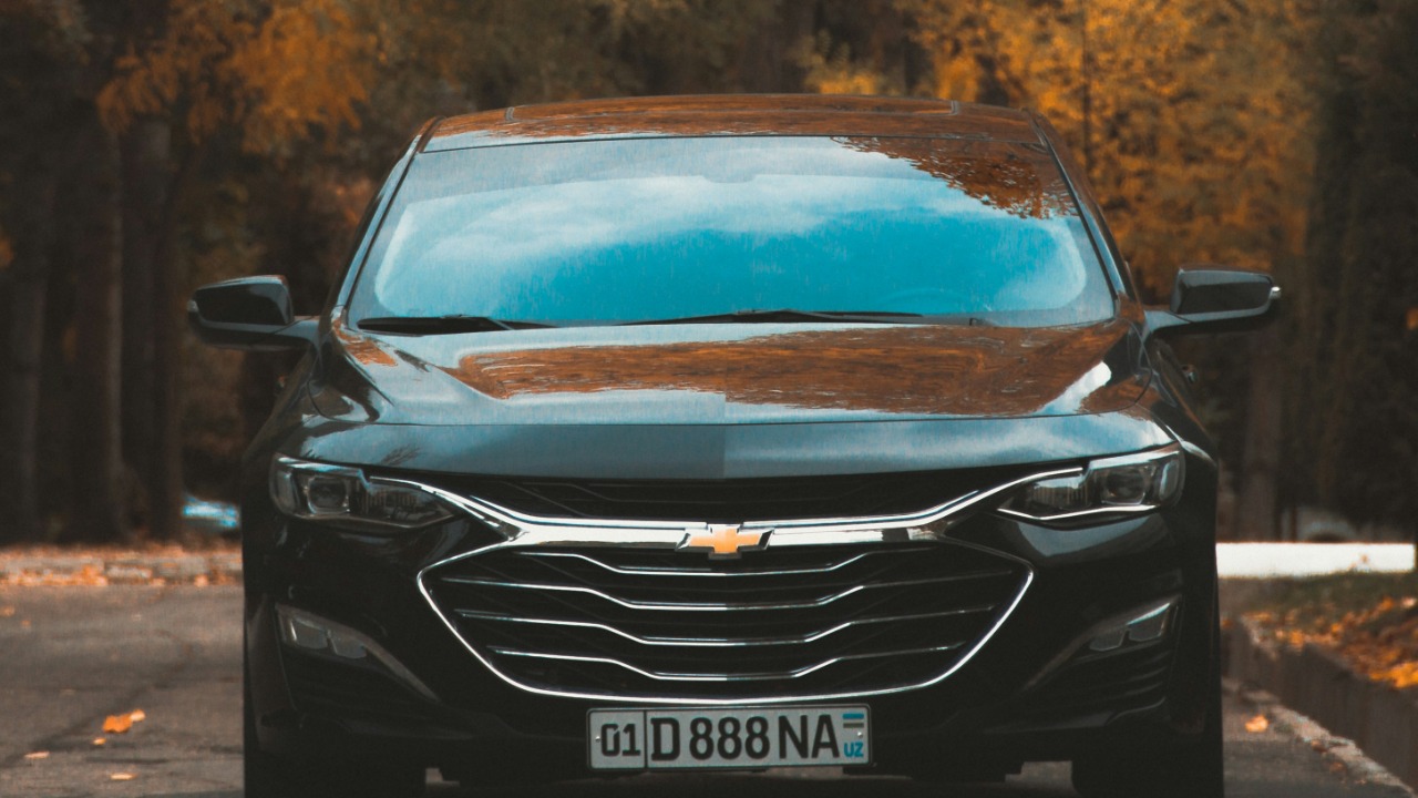 a car parked on the side of the road in front of a tree