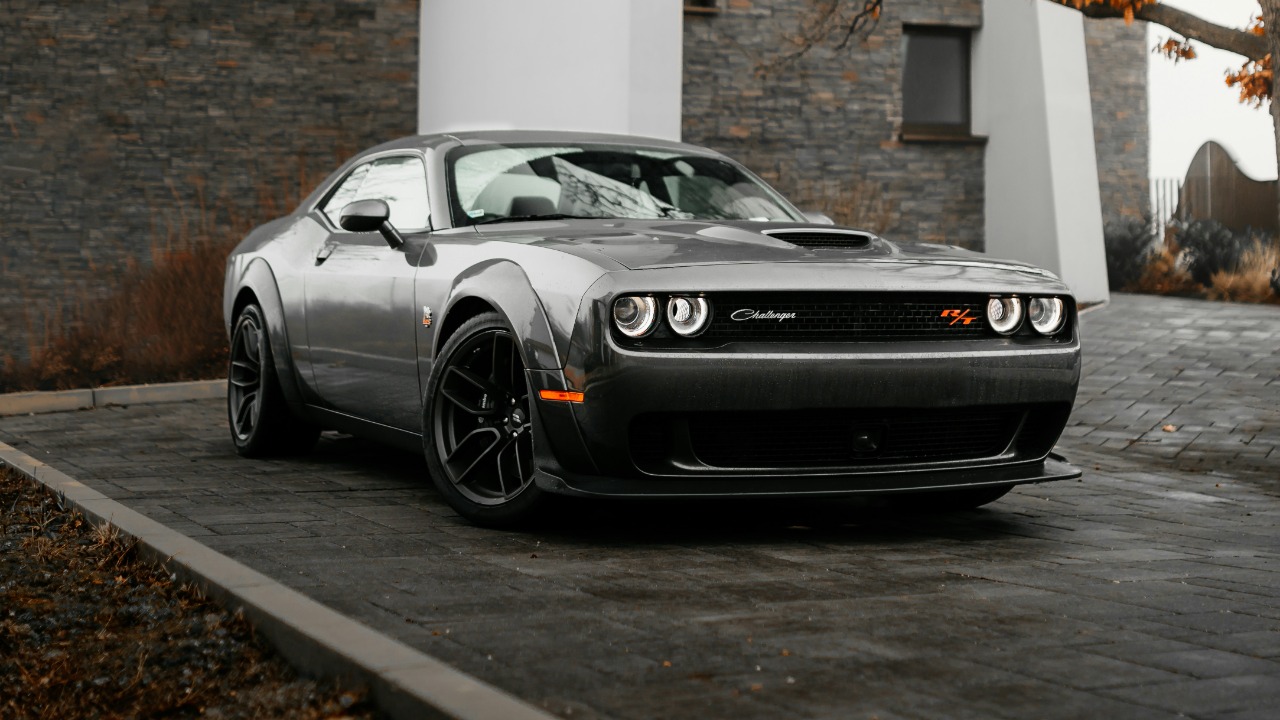 silver porsche 911 parked beside white concrete building during daytime