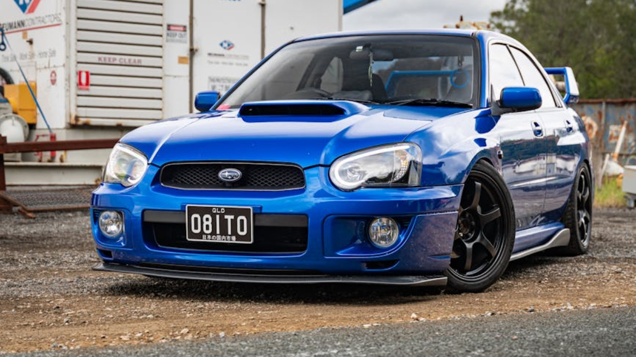 A blue Subaru WRX STI parked in an industrial area, emphasizing automotive culture and rugged style.