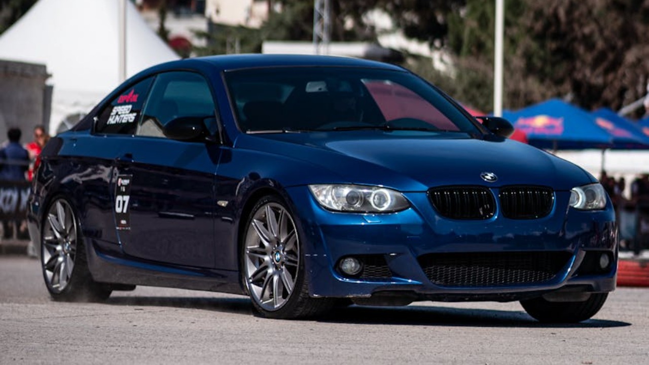 A sleek blue BMW Series 3 showcased at a car event in Tirana, Albania.