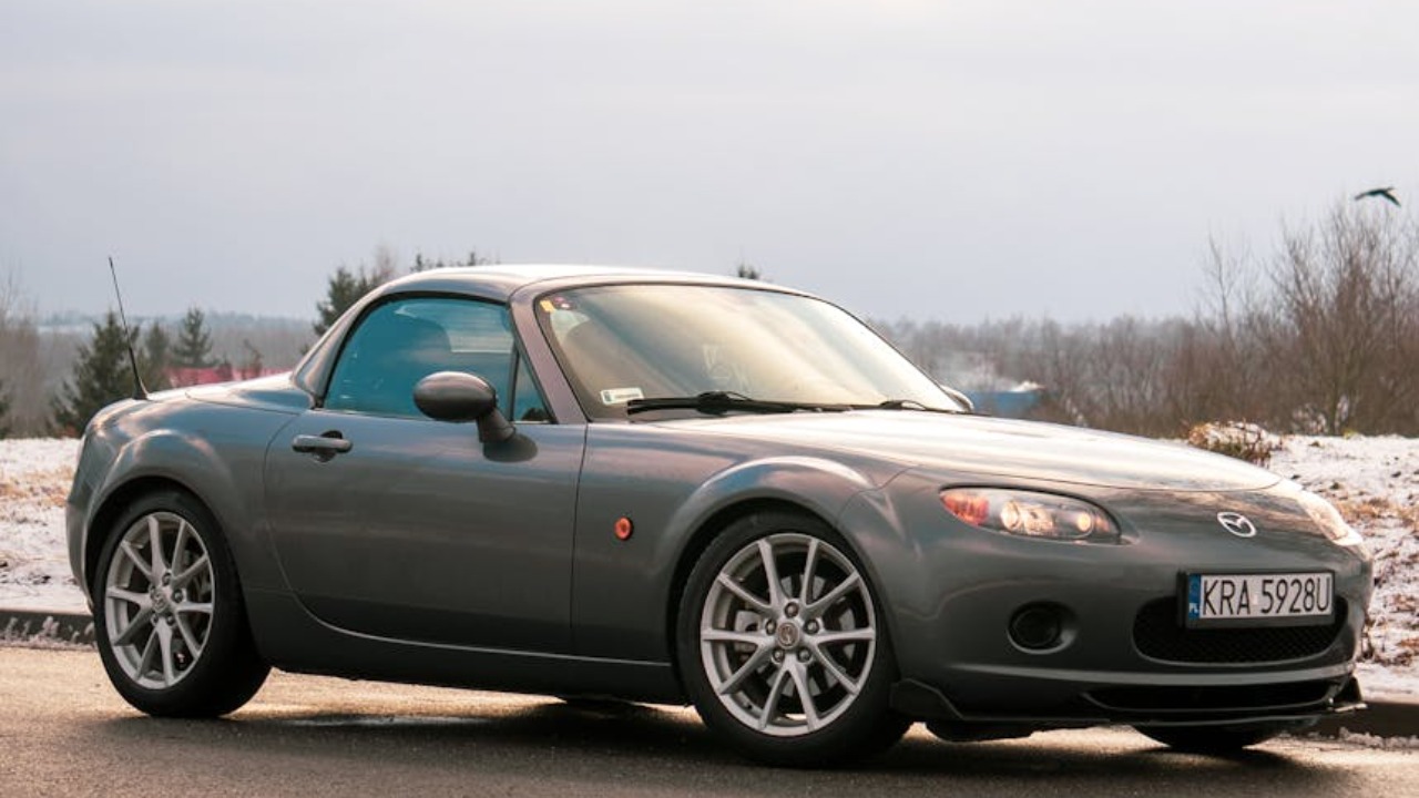 Silver Mazda Miata MX-5 parked on a snowy road in Kraków during the day.