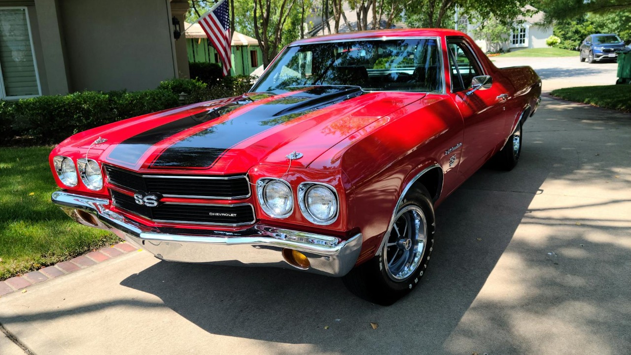 Classic red Chevrolet Chevelle with black stripes parked outdoors on a sunny day.