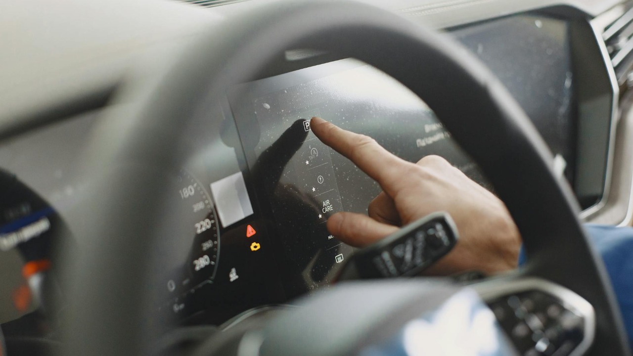 Close-up of a hand interacting with a car's digital dashboard. Modern technology and driving interface.