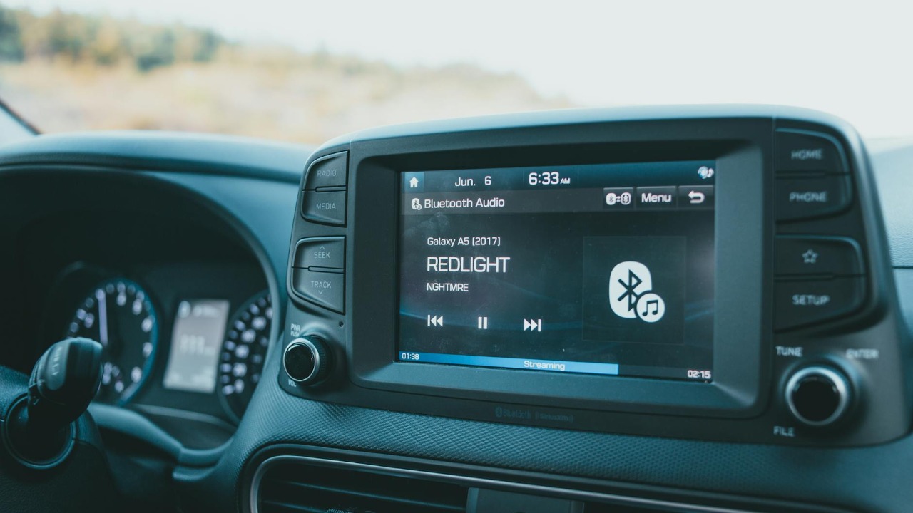 Close-up of a car dashboard featuring a Bluetooth audio system with music display.