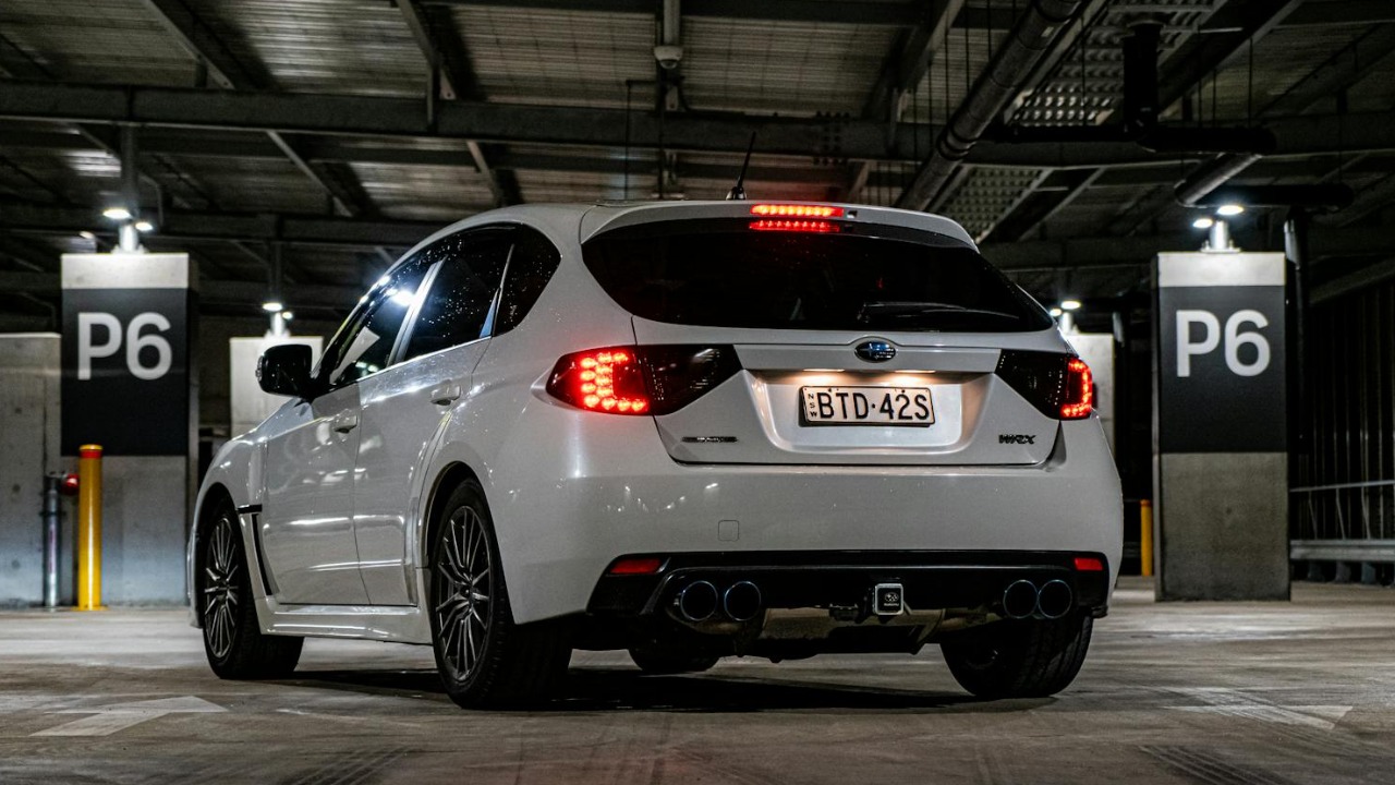 Sleek white car parked in a dimly lit underground parking garage with modern architecture.