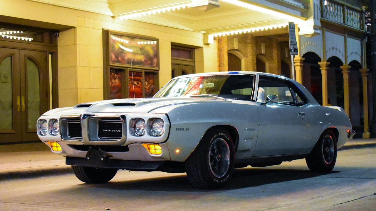 Vintage Pontiac Firebird Trans Am parked on a lit street at night.