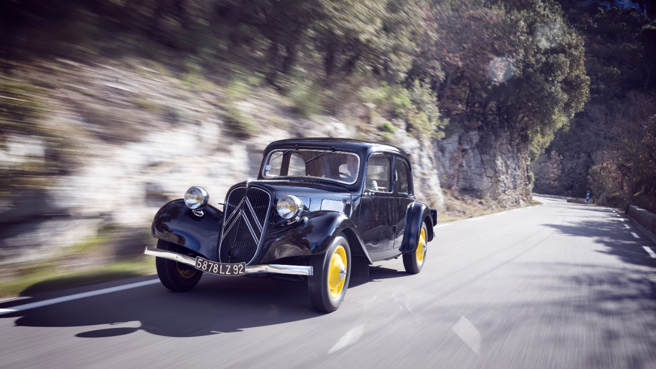 A black Citroën Traction Avant sedan on a mountain road