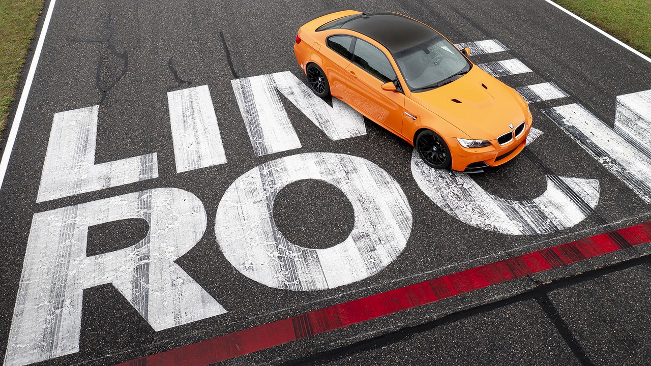 An orange 2013 BMW M3 Lime Rock Edition, an E92 M3, on the Lime Rock logo