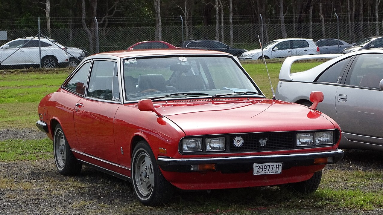 A red Isuzu 117 Coupe with the original round headlights